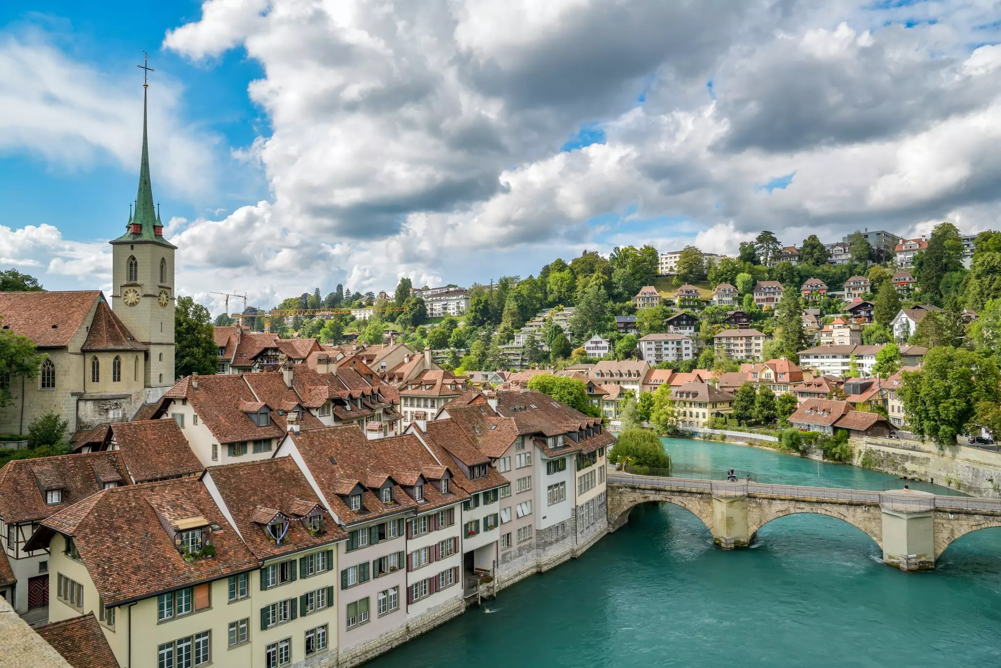A view of a river through a city, with historic stone buildings, churches and a bridge