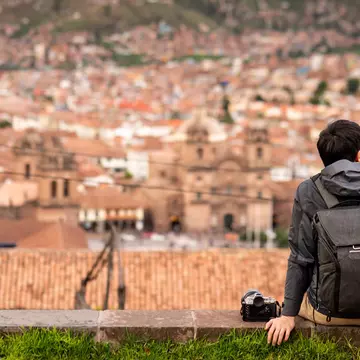 Tourist and photograpaher sitting on viewpoint looking at Cusco city.  Zephyr18 / Getty Images