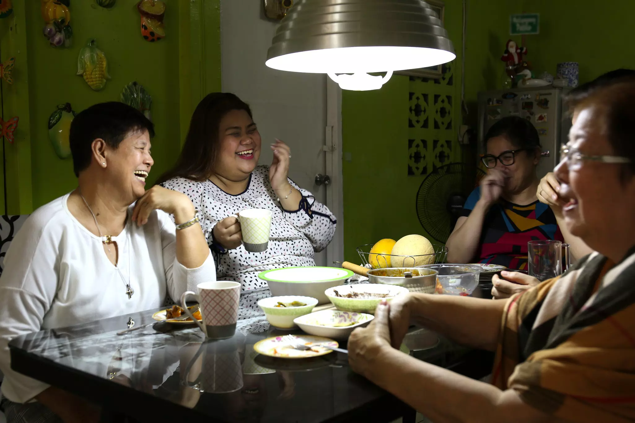 A group of people laugh while enjoying a meal around the dinner table in a private residence