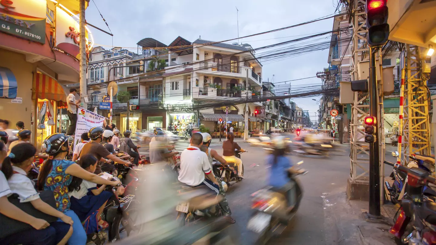 A busy street in HCMC with a crowd of scooters passing by in a blur