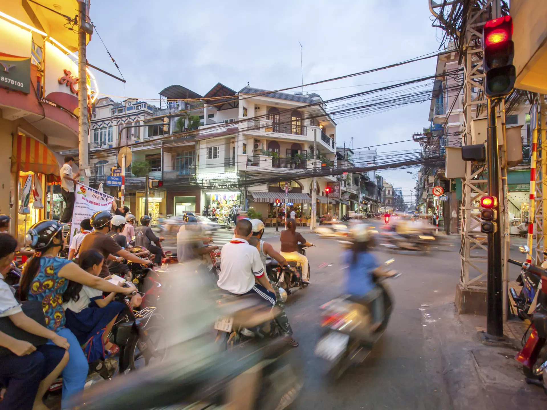A busy street in HCMC with a crowd of scooters passing by in a blur