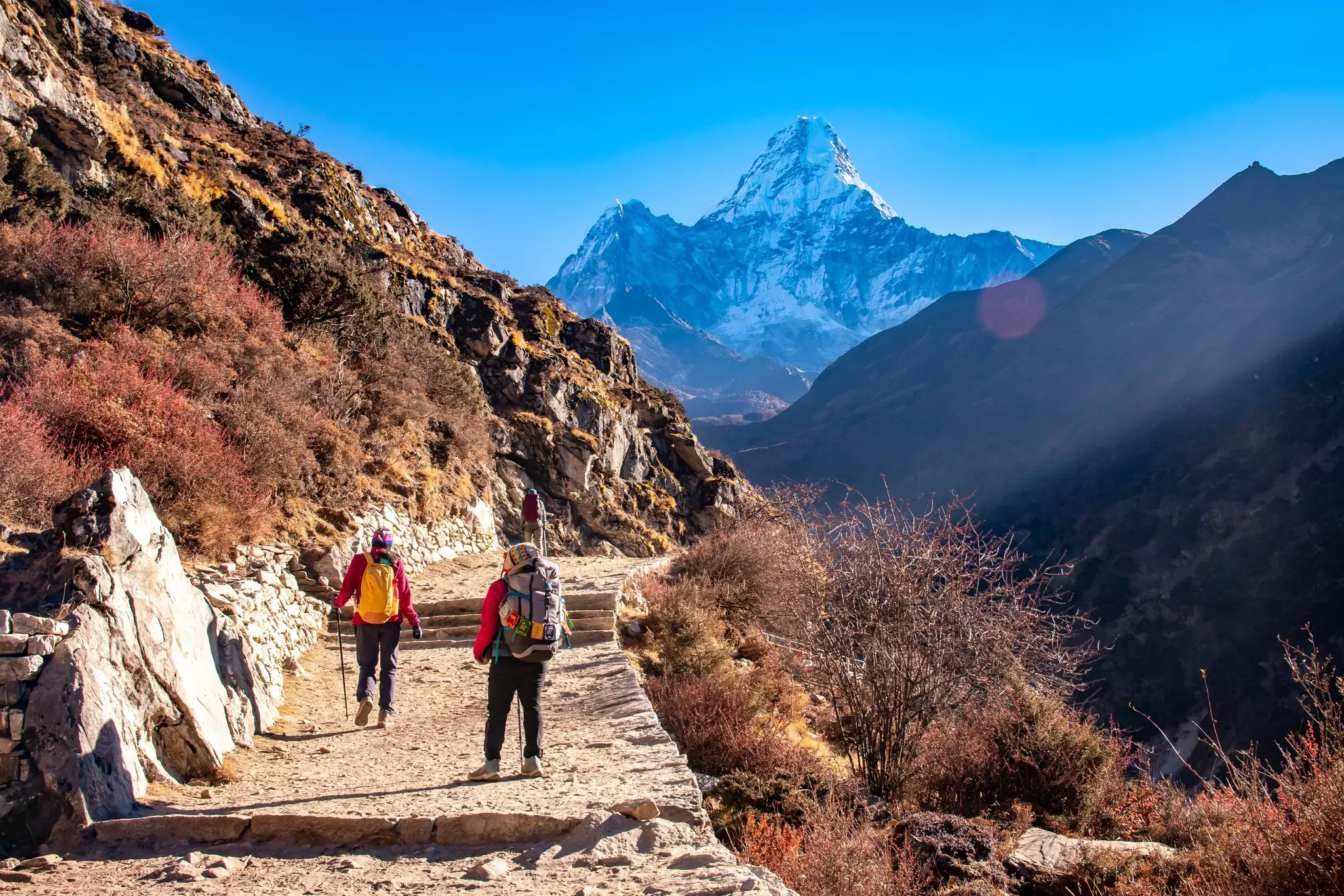 People trekking on Everest Base Camp, with a view of Mt Ama Dablam in the background