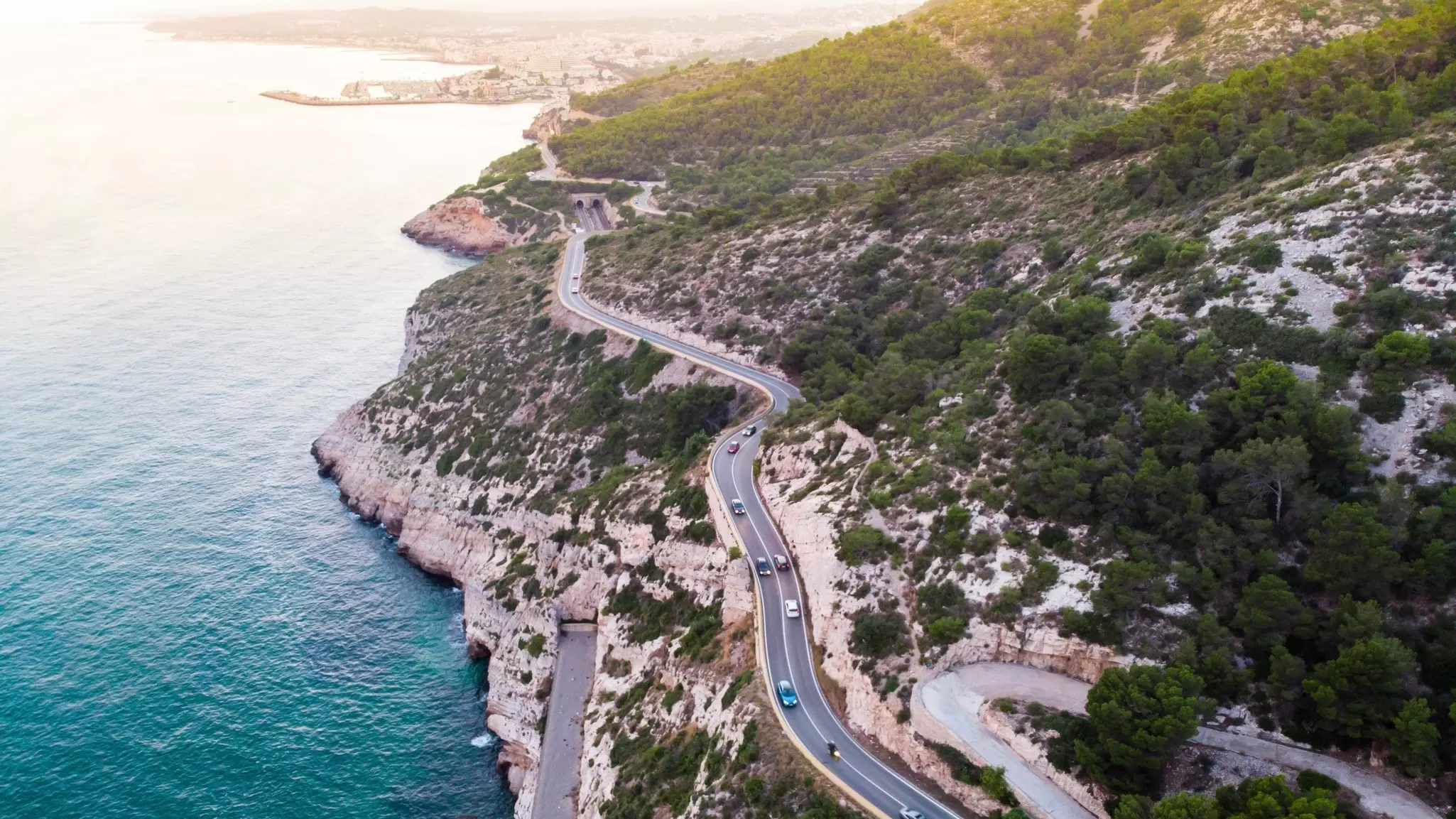 A road curves between the cliffs overlooking the sea near Garraf Beach.