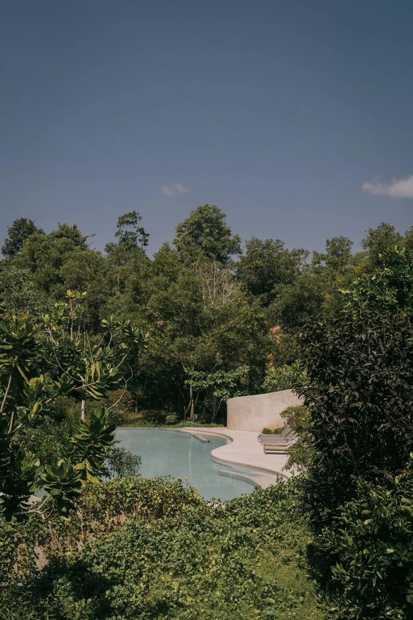 A large clear pool encircled by small lamps sits in front of a wooden pool-side restaurant; eco luxury resorts