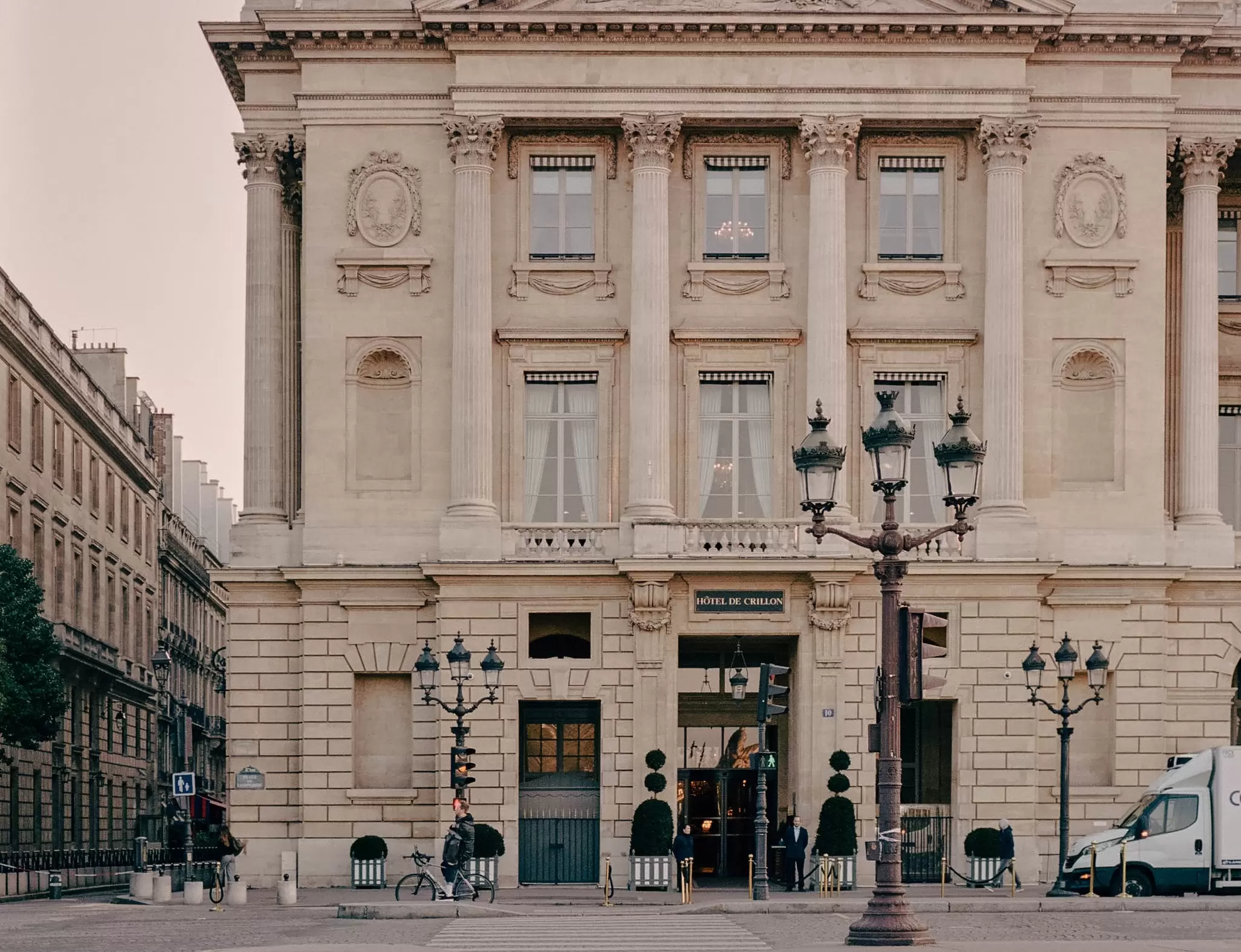 Exterior of a large, ornate building with three-pronged streetlamps on the sidewalk in front.