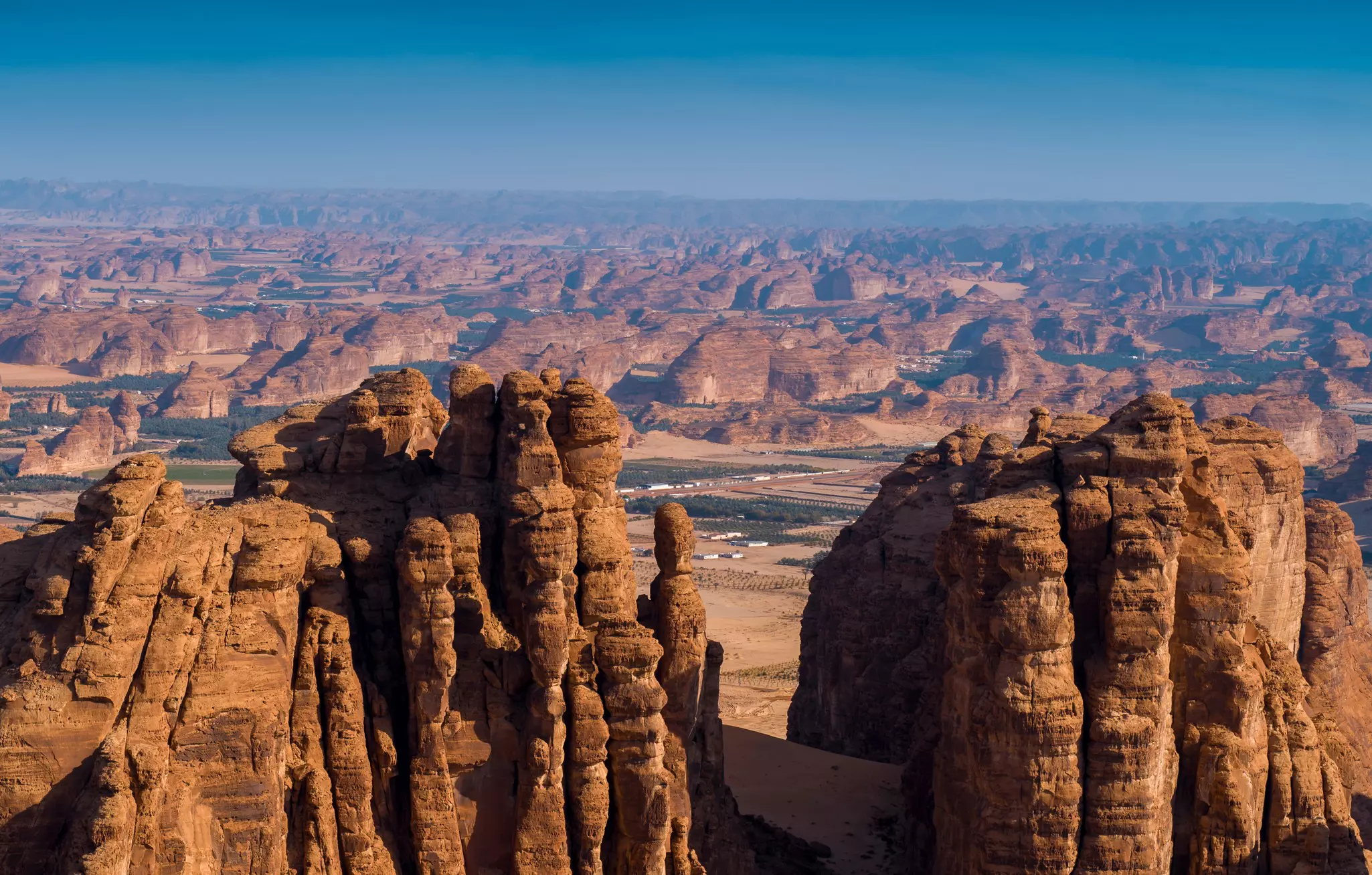 A city in a desrt valley surrounded by rock formations.