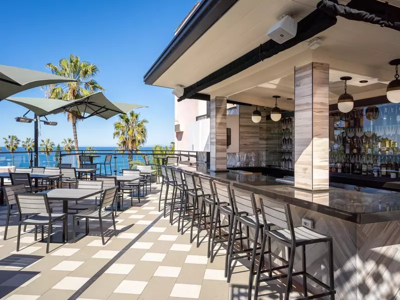 Stools lined up at a bar on a rooftop lounge.