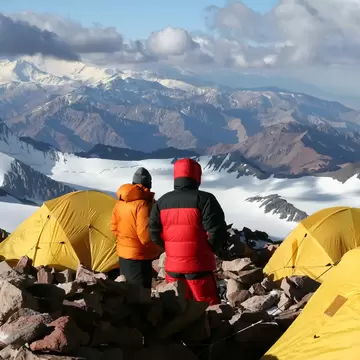 Alpine climbers acclimating at camp two of Aconcagua with bright yellow tents. Parque Provincial Aconcagua, Argentina.