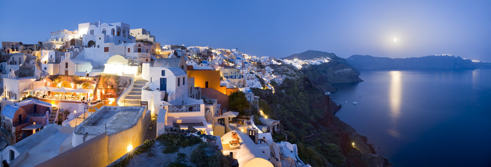 Rooftops of houses and villas on rim of caldera at dusk.
