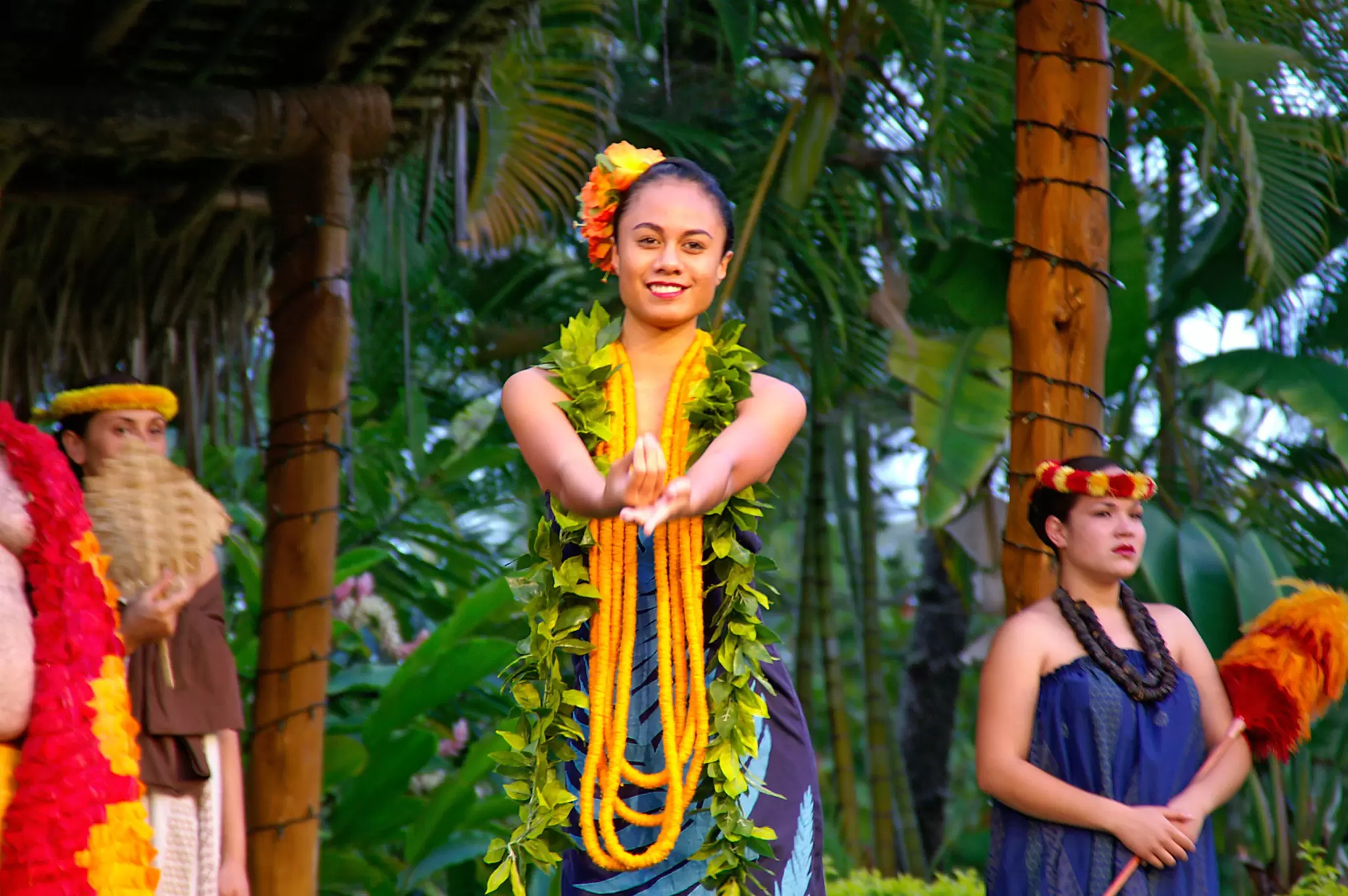 A woman smiles and extends her hands during a hula performance at Polynesian Cultural Center on Oʻahu.