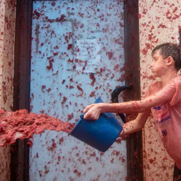 A bucket of crushed tomatoes might get hurled your direction at any time during the world's biggest - and messiest - tomato throwing festival in Spain. Lonely Planet/Getty
