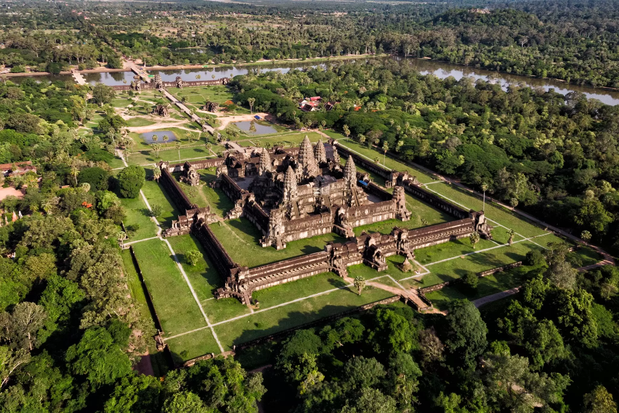 Aerial view of Angkor Wat temple, Siem Reap, Cambodia. Stone walled buildings surrounded by a perimeter wall and green grass and trees