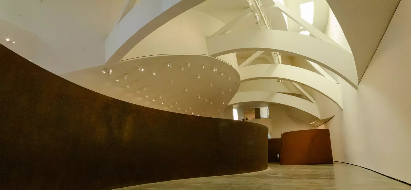 A long rusted metal sculpture in a museum gallery.