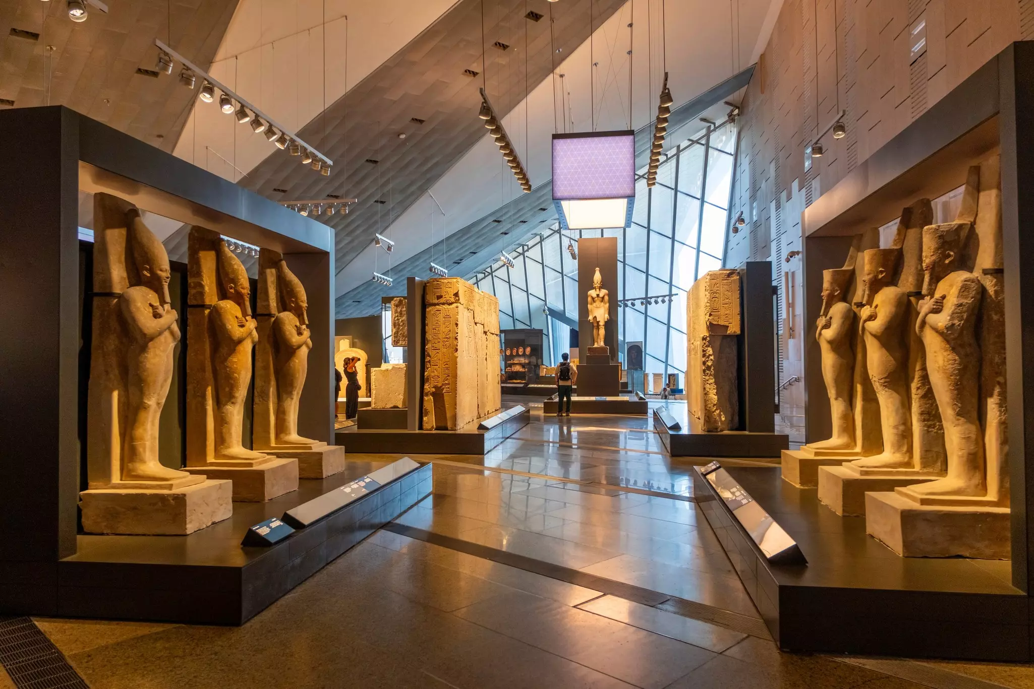A large exhibition room within a museum lined with stone statues and large engraved stones.