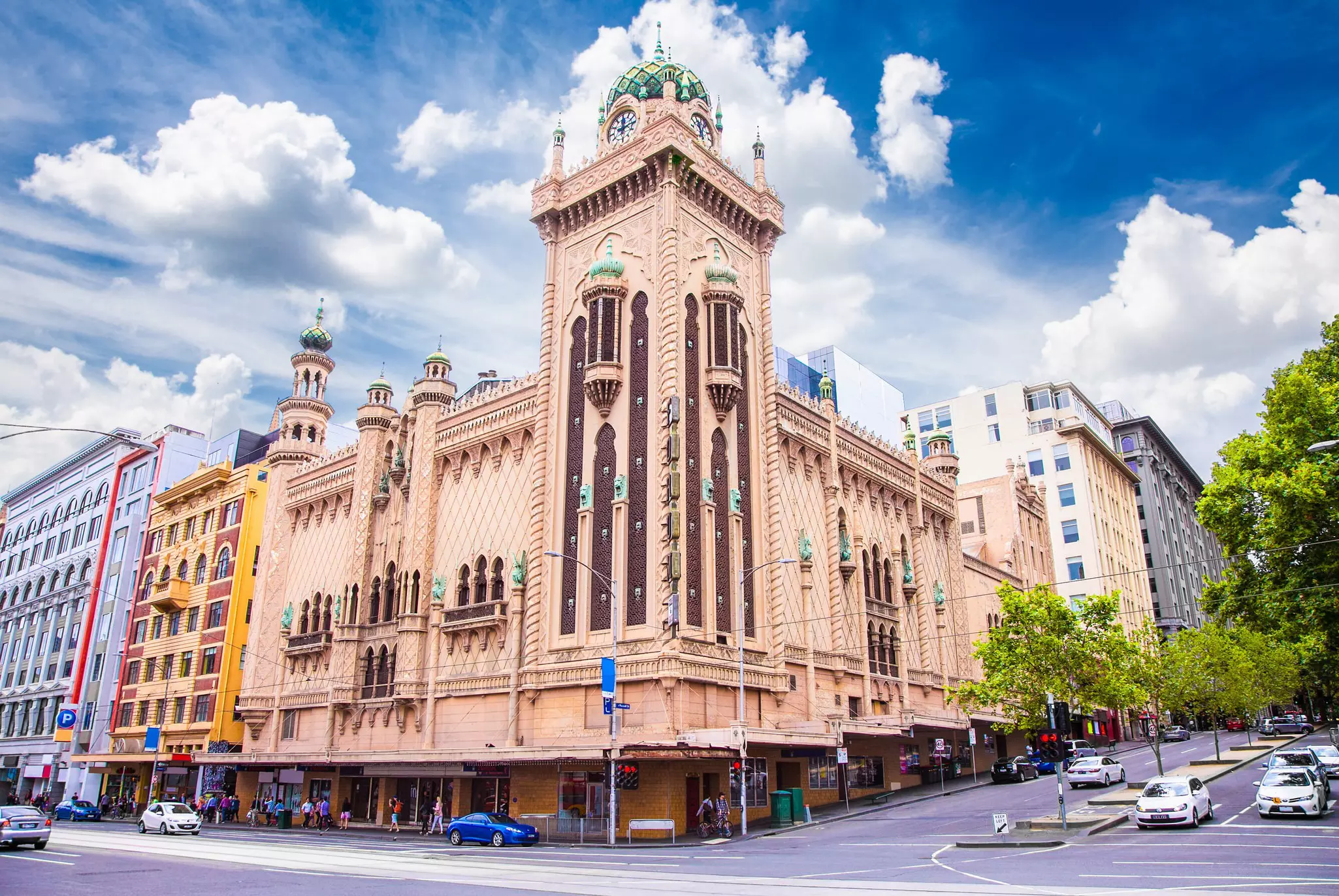 A theater building with a Moorish Revival-style exterior at the corner of a busy road intersection in a city.