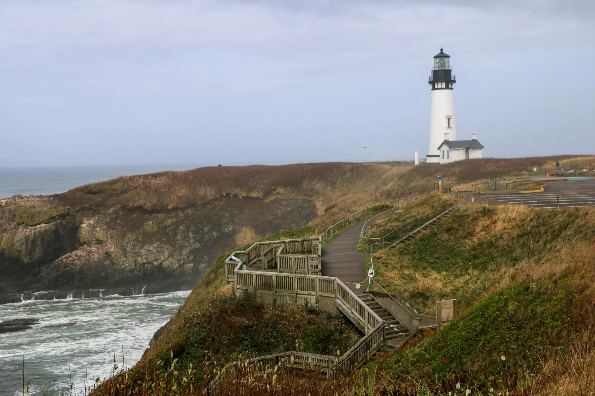 Photo of Yaquina Head Lighthouse overlooking the beach with stairway in the foreground, Newport, Oregon. 