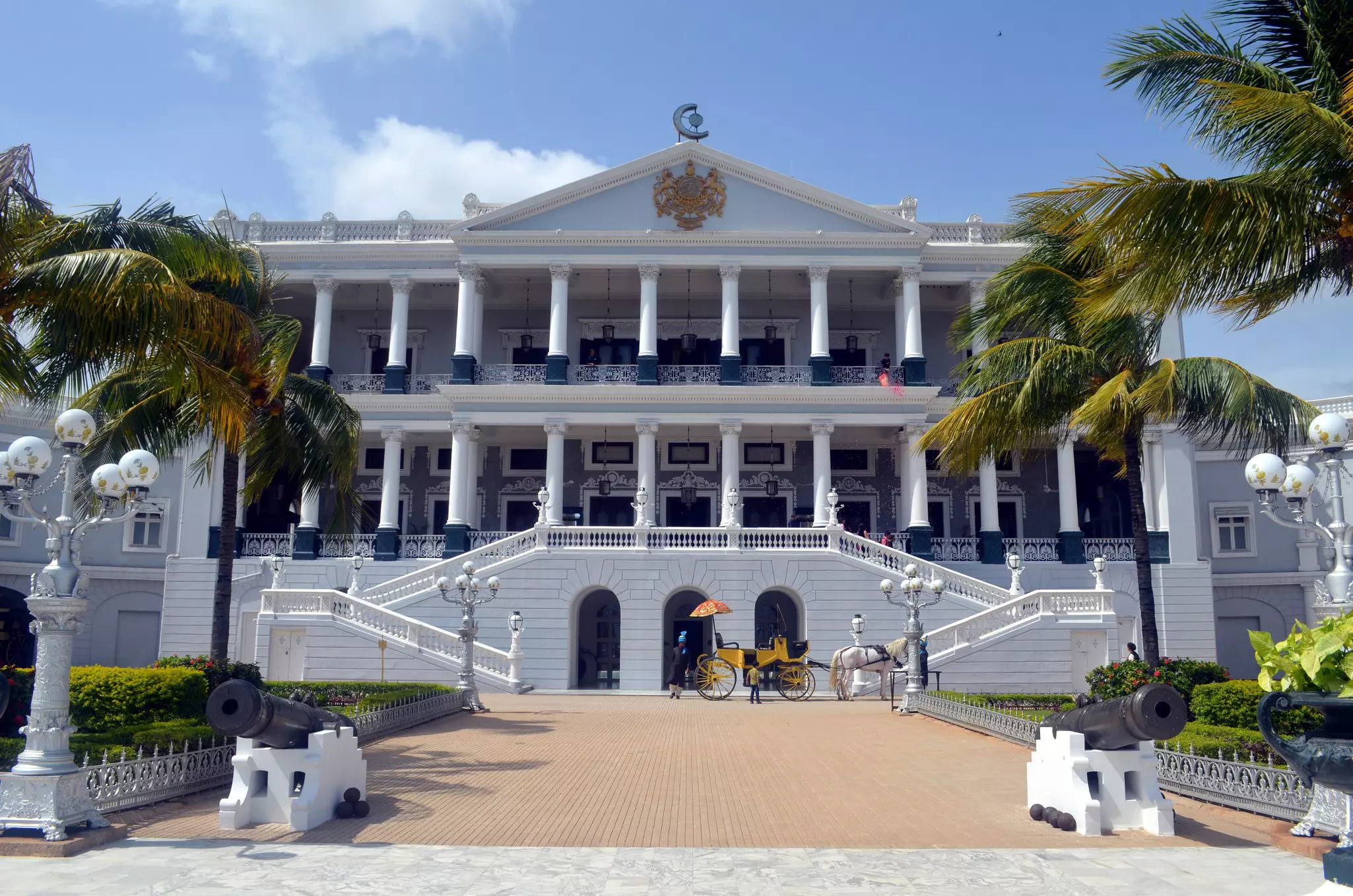 A horsedrawn carriage stands at the foot of a staircase leading up to a multi-columned palace building