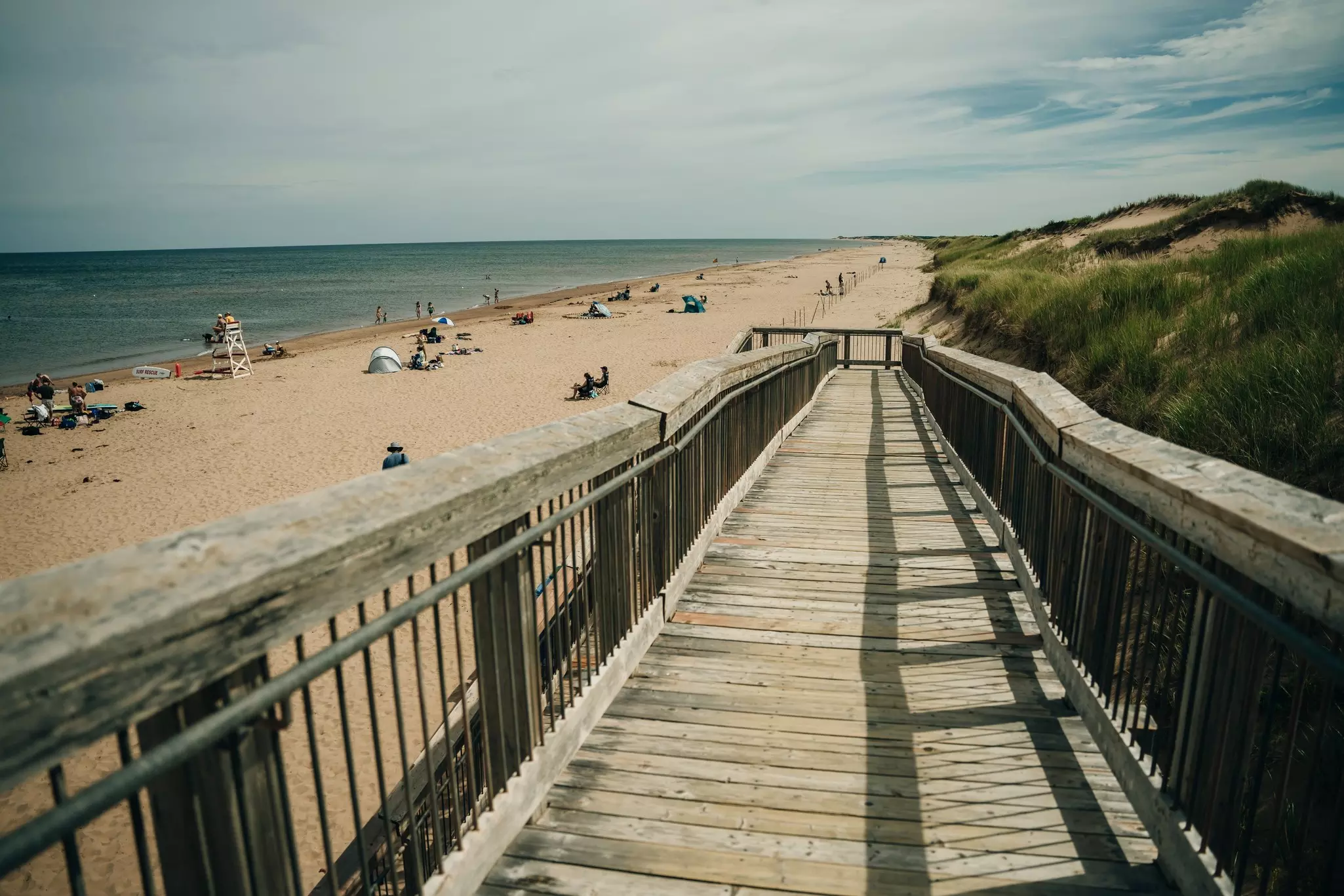 A wooden ramp leads past dunes down to a sandy oceanfront beach.
