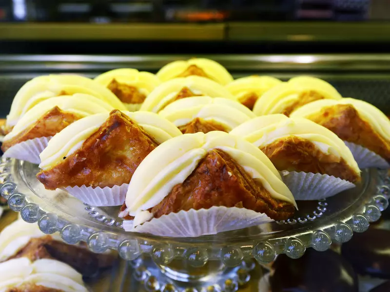 A round glass platter of triangular pastries filled with cream.