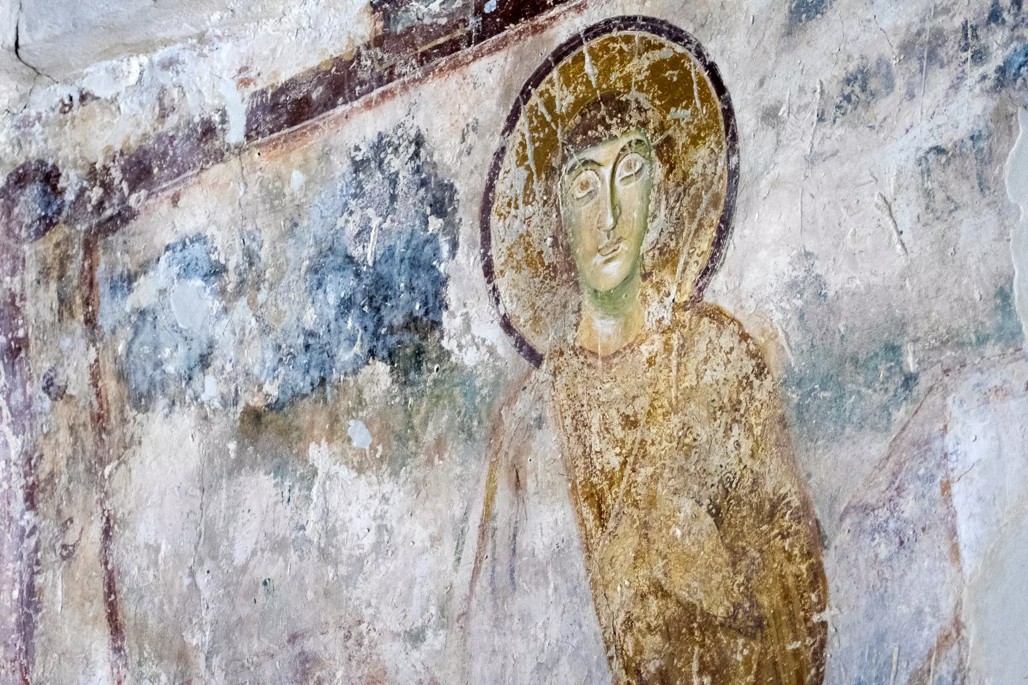 An ancient fresco depicts military saint with a halo. The fresco has degraded over time.