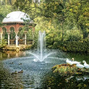 A Moorish-style pavilion by a pond with white ducks at María Luisa Park, Seville, Spain