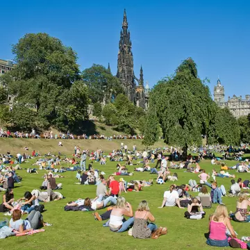 People enjoying a summer day in Edinburgh’s Princes Street Gardens. Fabio Pagani / Shutterstock