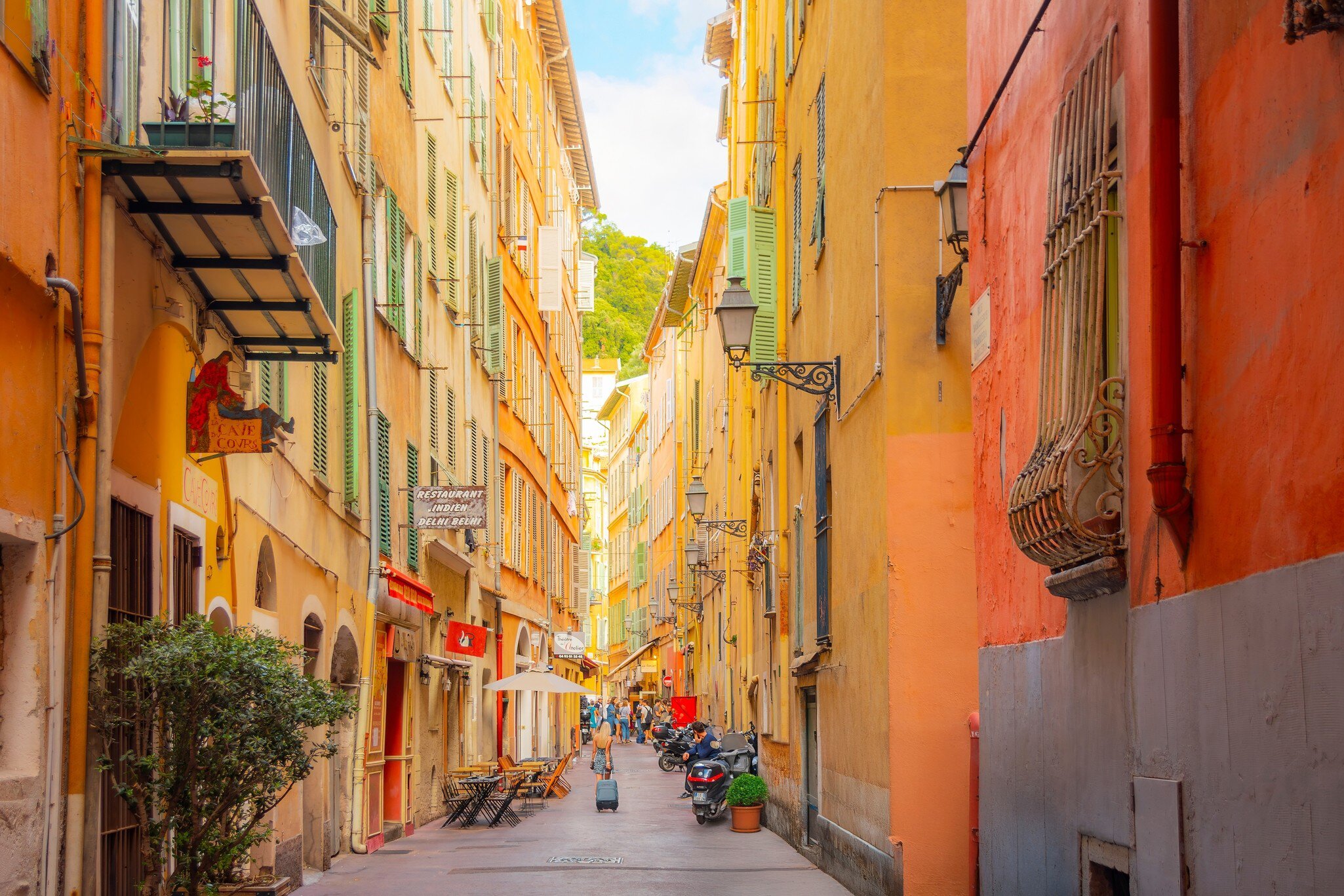 Nice, France. A tourist pulls her suitcase along a narrow alley in the colorful Vieux Nice Old town of Nice, France, on the French Riviera, Cote d'Azur of the Mediterranean Sea.