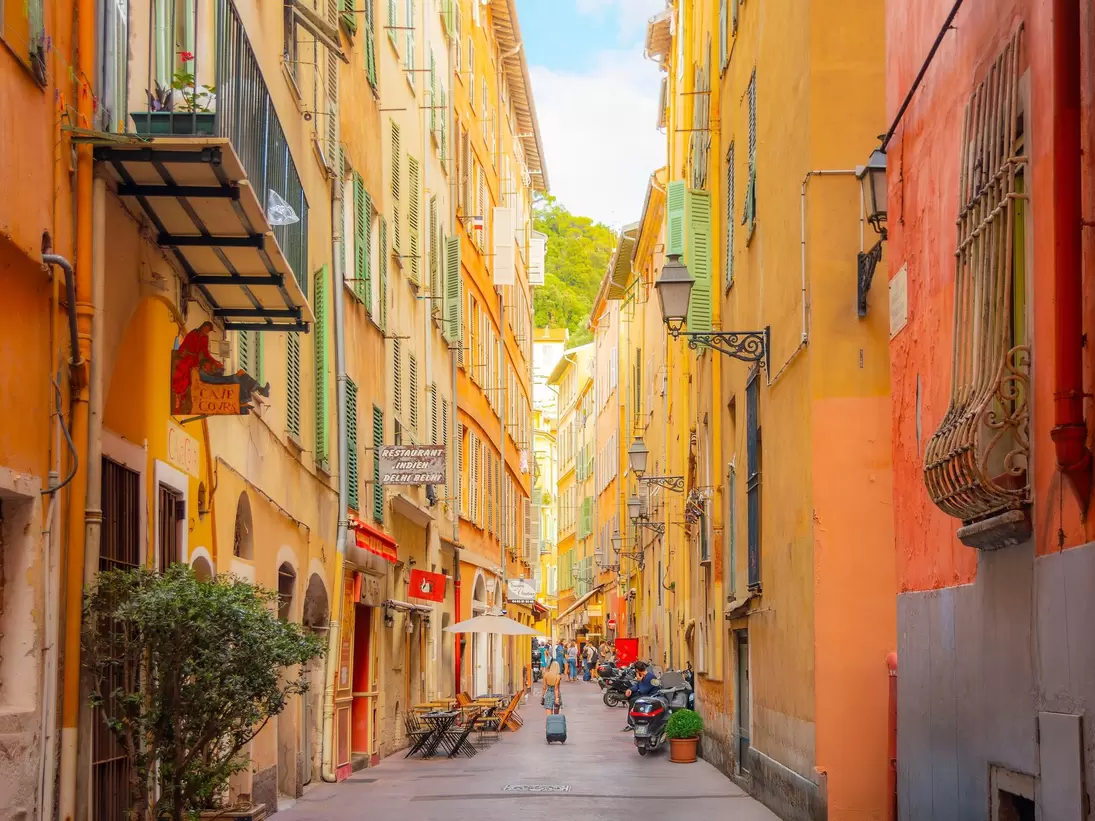 Nice, France. A tourist pulls her suitcase along a narrow alley in the colorful Vieux Nice Old town of Nice, France, on the French Riviera, Cote d'Azur of the Mediterranean Sea.