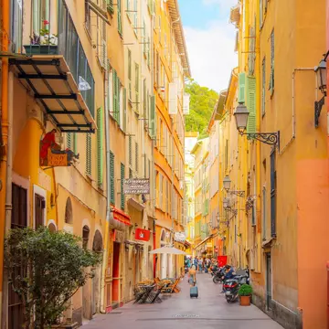 Nice, France. A tourist pulls her suitcase along a narrow alley in the colorful Vieux Nice Old town of Nice, France, on the French Riviera, Cote d'Azur of the Mediterranean Sea.