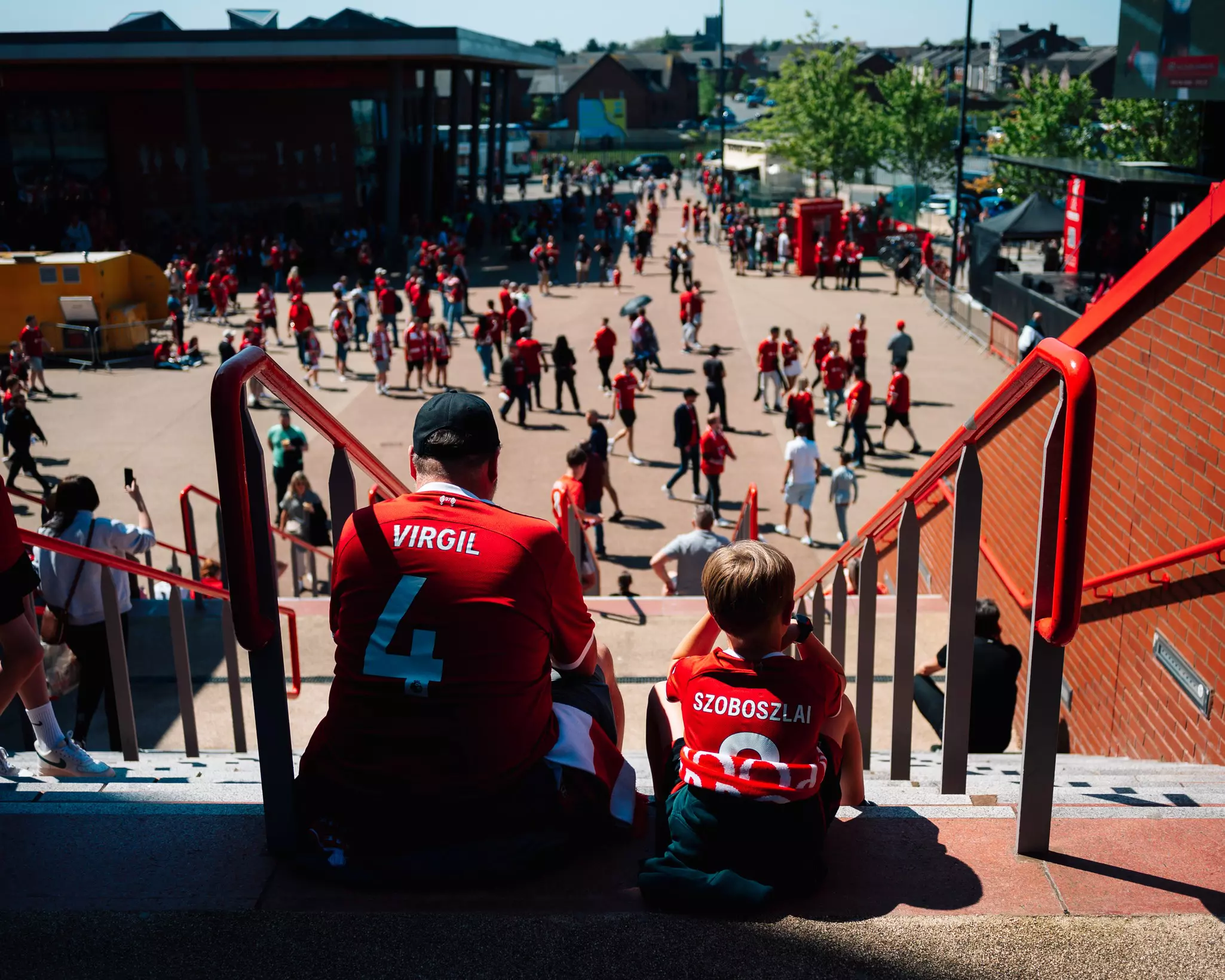 A father and son wait for doors to open at Liverpool's Anfield Stadium in 2024.