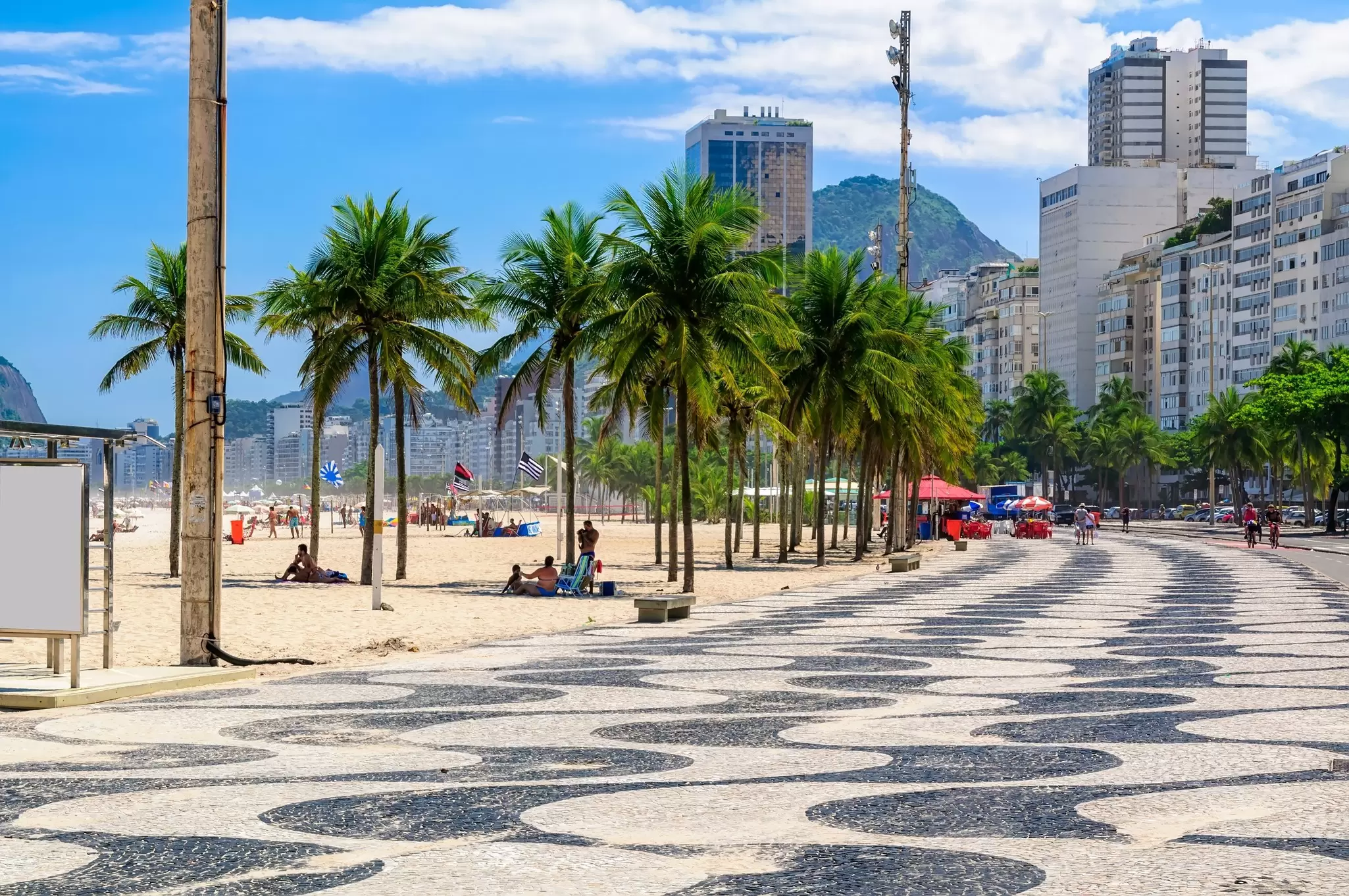 View along the boardwalk by Copacabana Beach lined with palm trees in Rio de Janeiro, Brazil.
