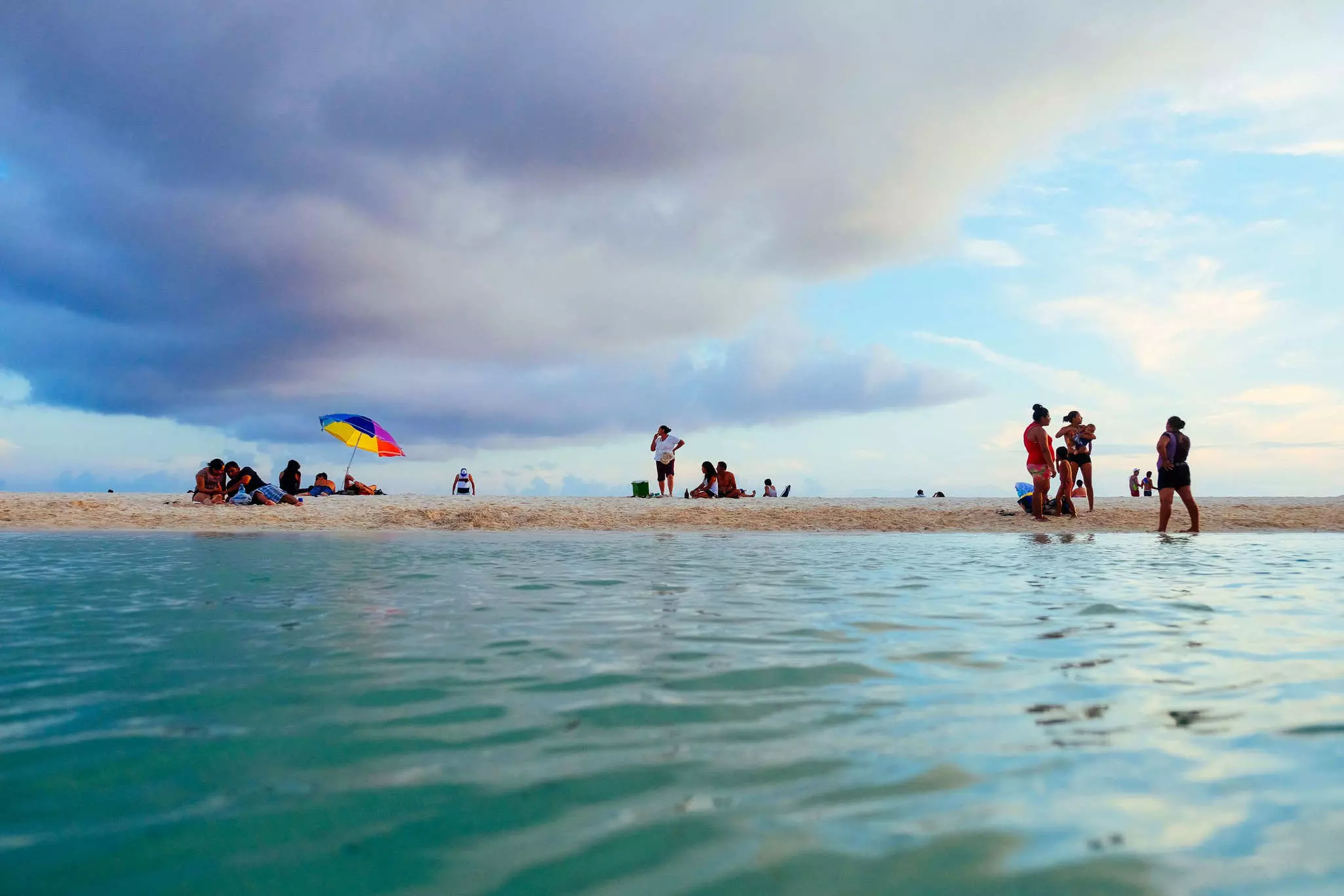 Locals on the shore of a small cenote, as seen from the water