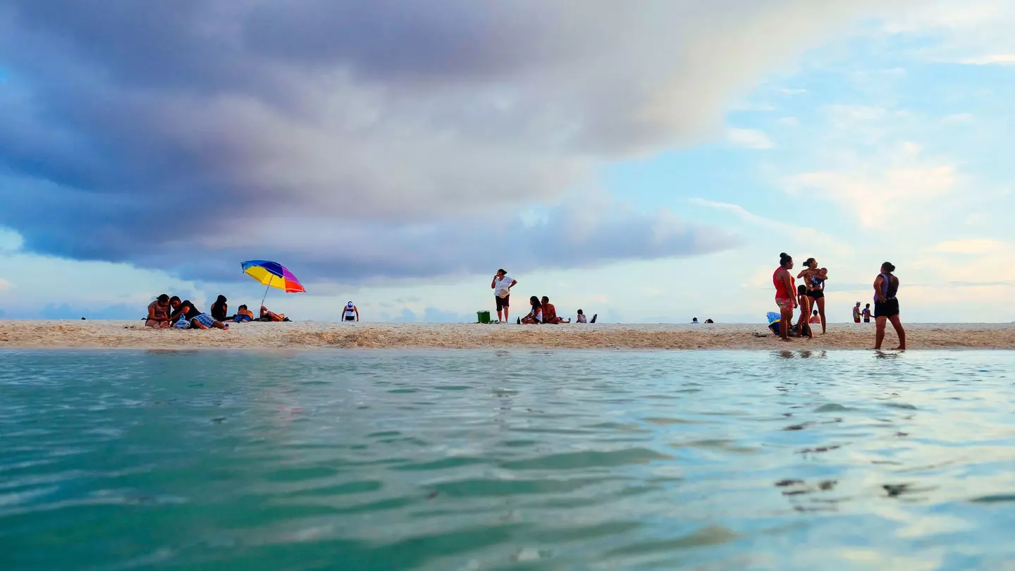 Locals on the shore of a small cenote, as seen from the water