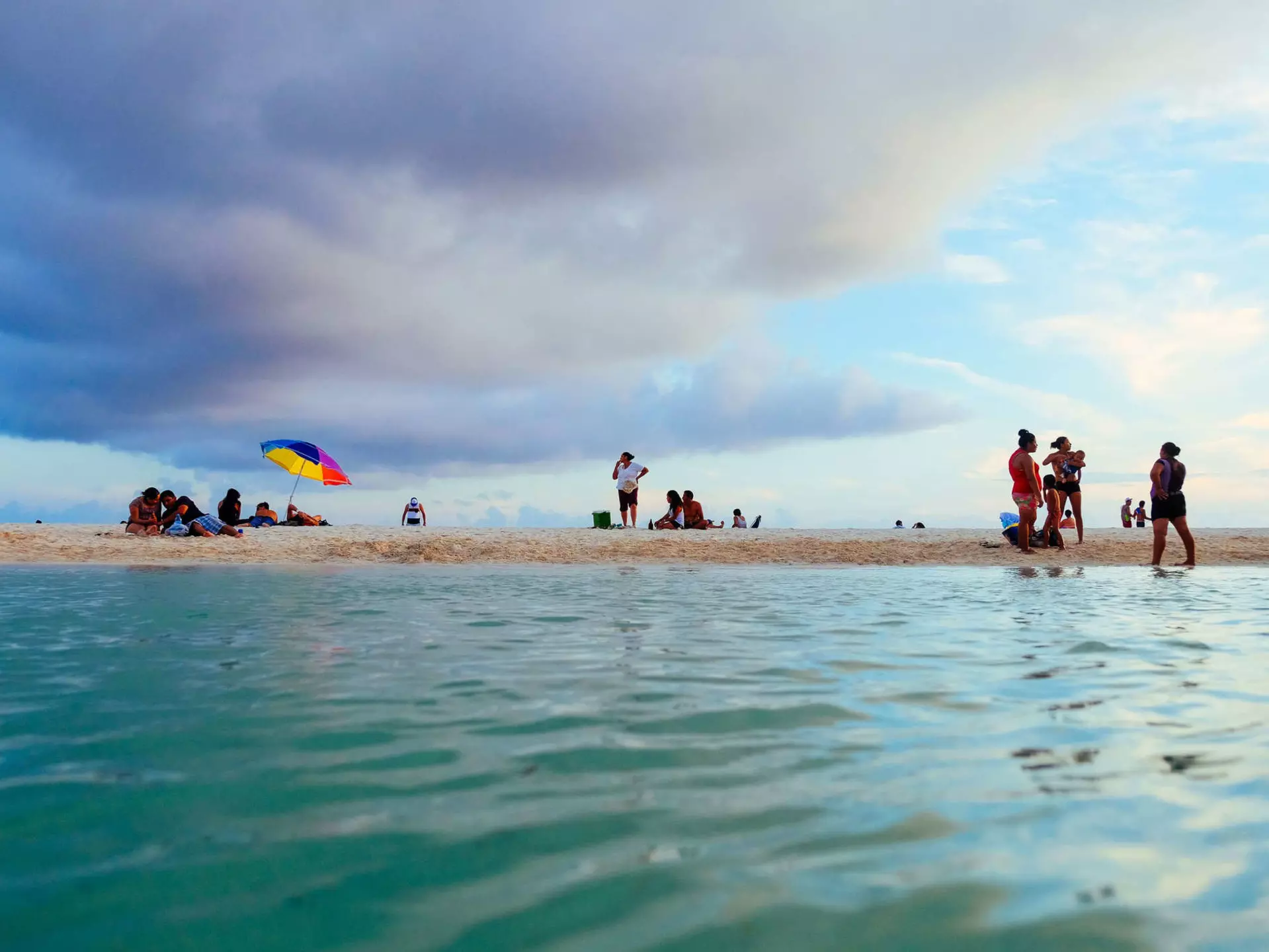 Locals on the shore of a small cenote, as seen from the water