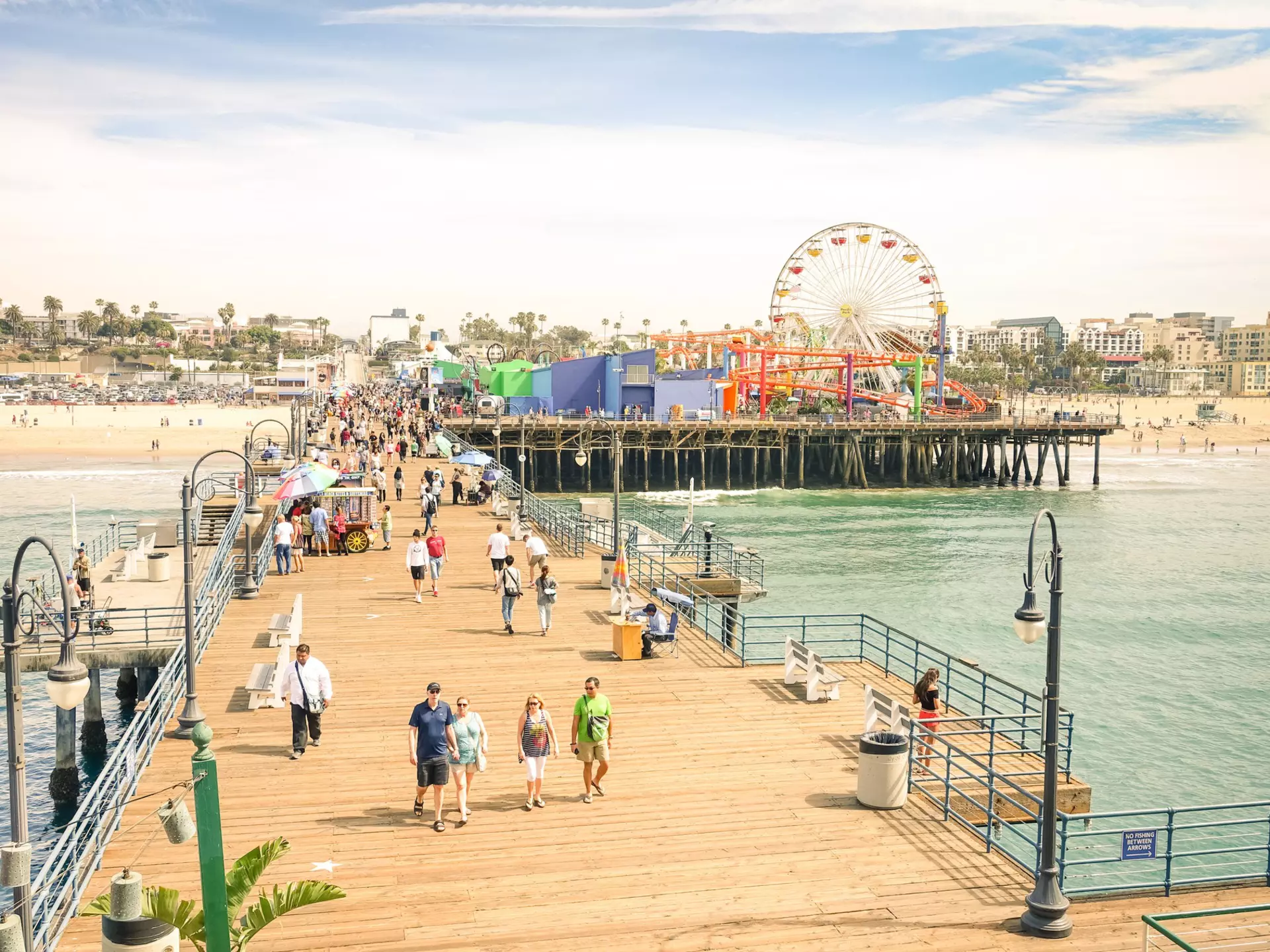 Aerial view of tourists and locals at Santa Monica Pier with the Pacific Amusement Park in the background.