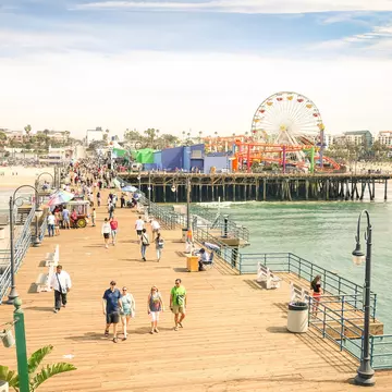 Aerial view of tourists and locals at Santa Monica Pier with the Pacific Amusement Park in the background.