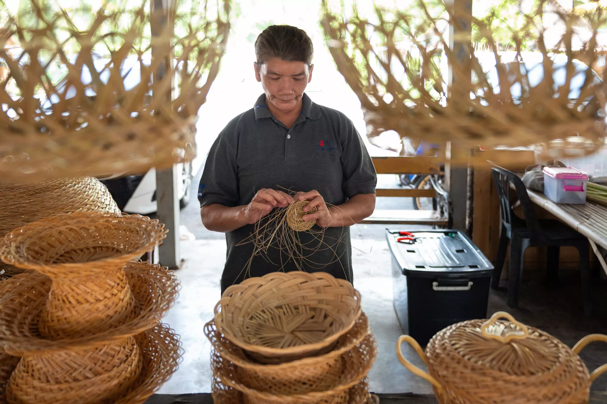 A weaver in their studio creating baskets from dried palm fronds.