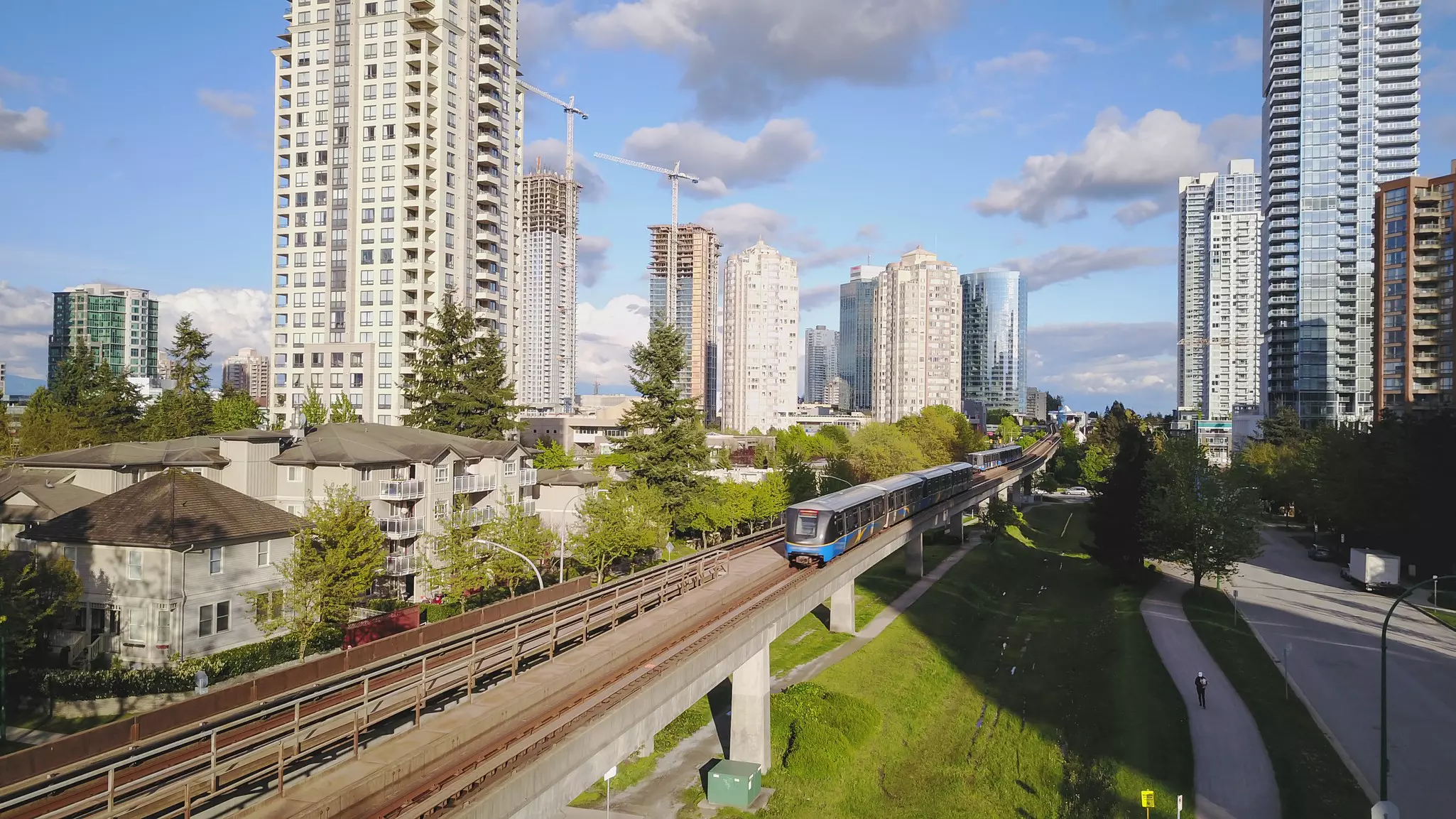 Two trains run on an elevated track between high-rise residences.