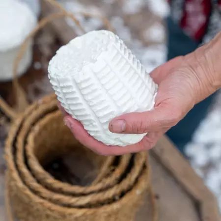 A hand holds a firm, white mold of cheese made from fresh goat's milk.