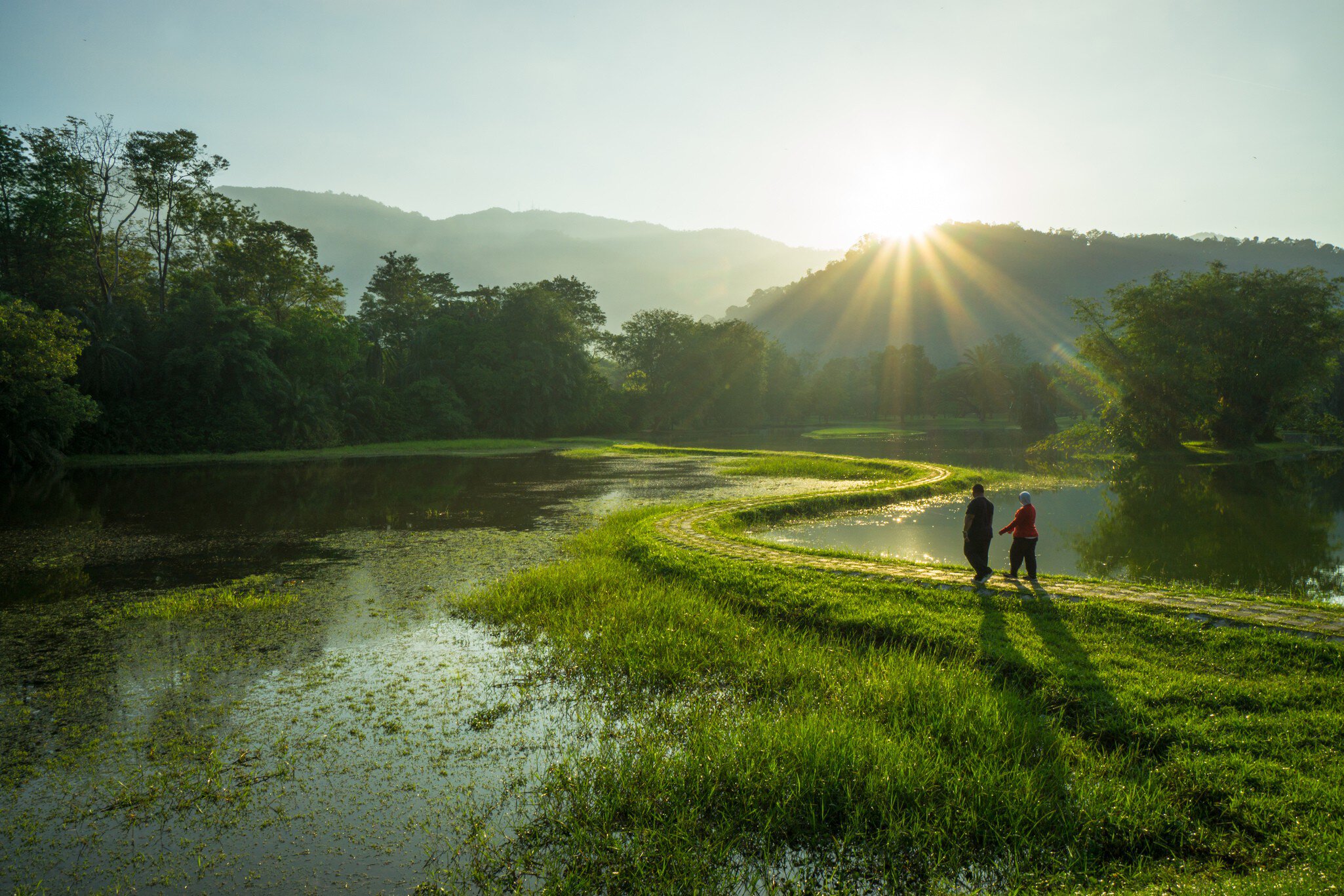 Couple walking at the pathway of 'S - Curve' in early morning at Taman Tasik Taiping, Perak, Malaysia.