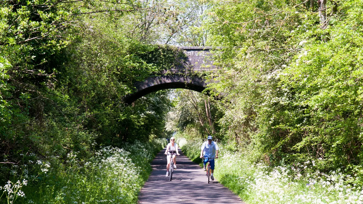A couple cycling on the Bristol and Bath Railway Path in spring.