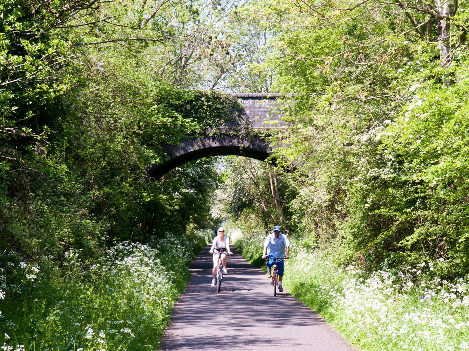 A couple cycling on the Bristol and Bath Railway Path in spring.