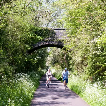 A couple cycling on the Bristol and Bath Railway Path in spring.