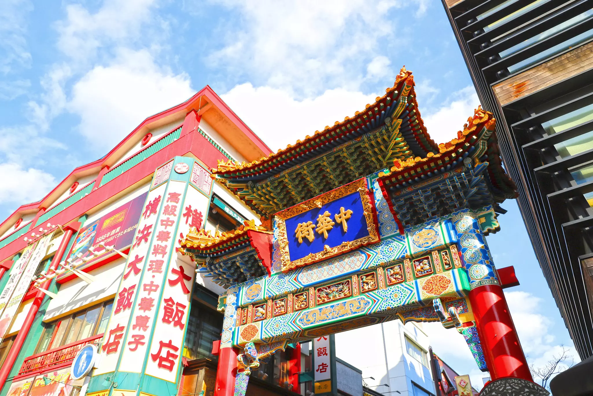 Looking up at a colorful gate leading into a Chinatown neighborhood on a sunny day.