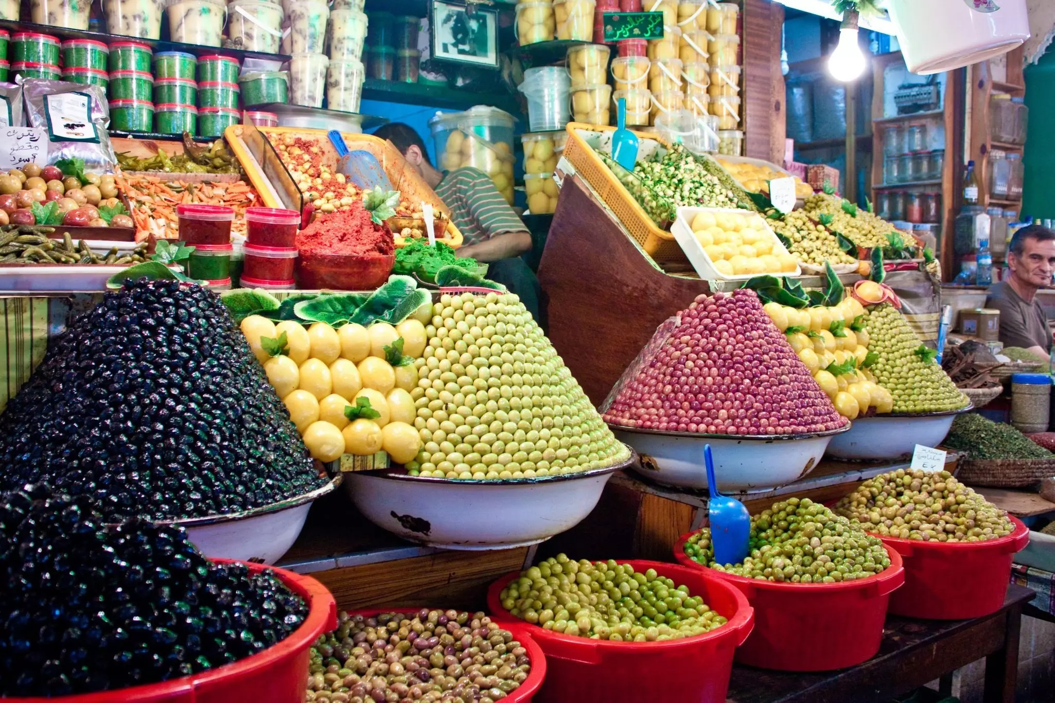 Different types of olives in bins and stacked into cone shapes at a market in Morocco.