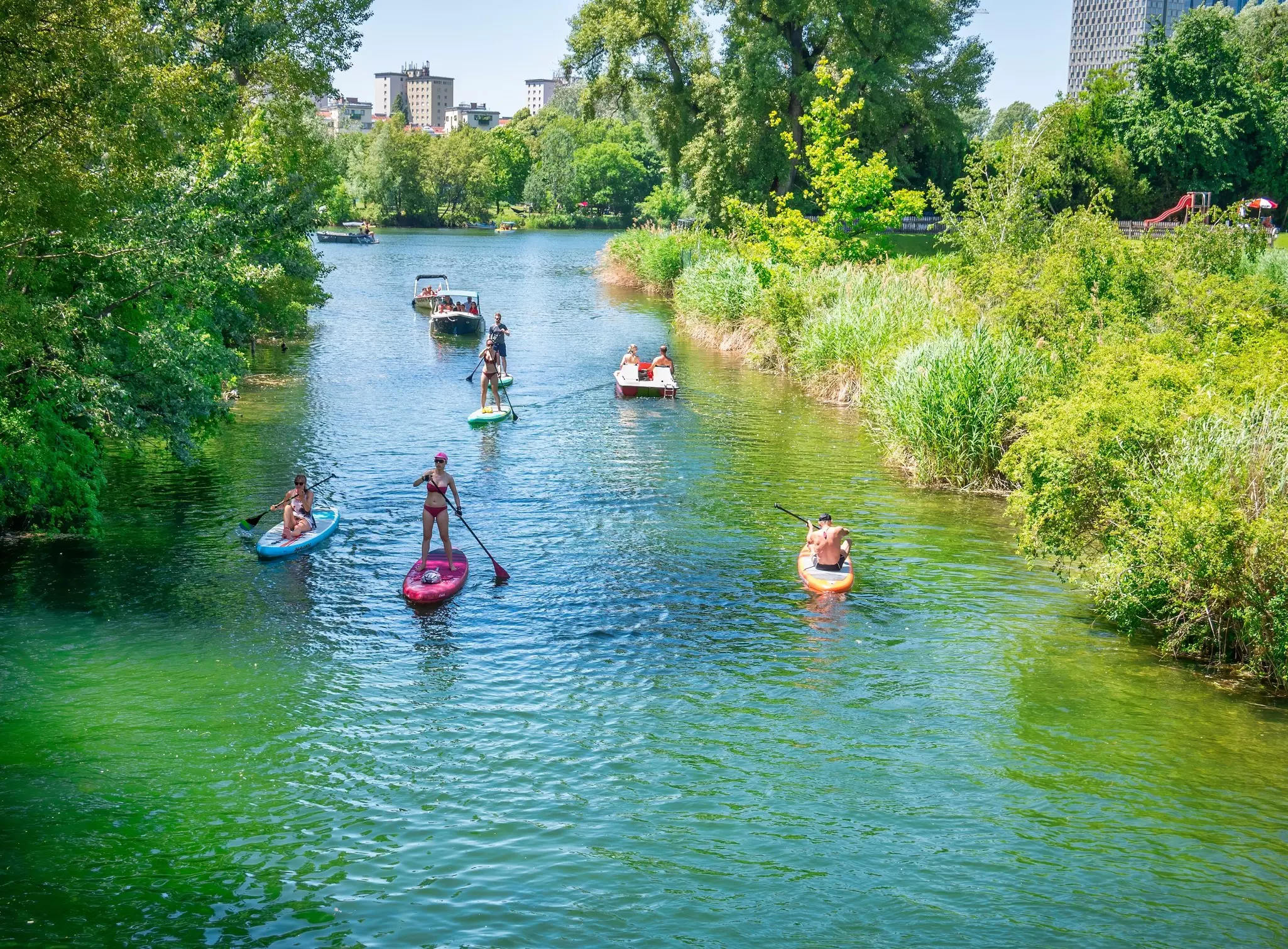 Vienna, Austria - June 2022: Summer landscape at the beach  with people paddling in kayaks and stand up boards in Kaiserwasser Alte Donau park ( Strandbad Gansehaufel)