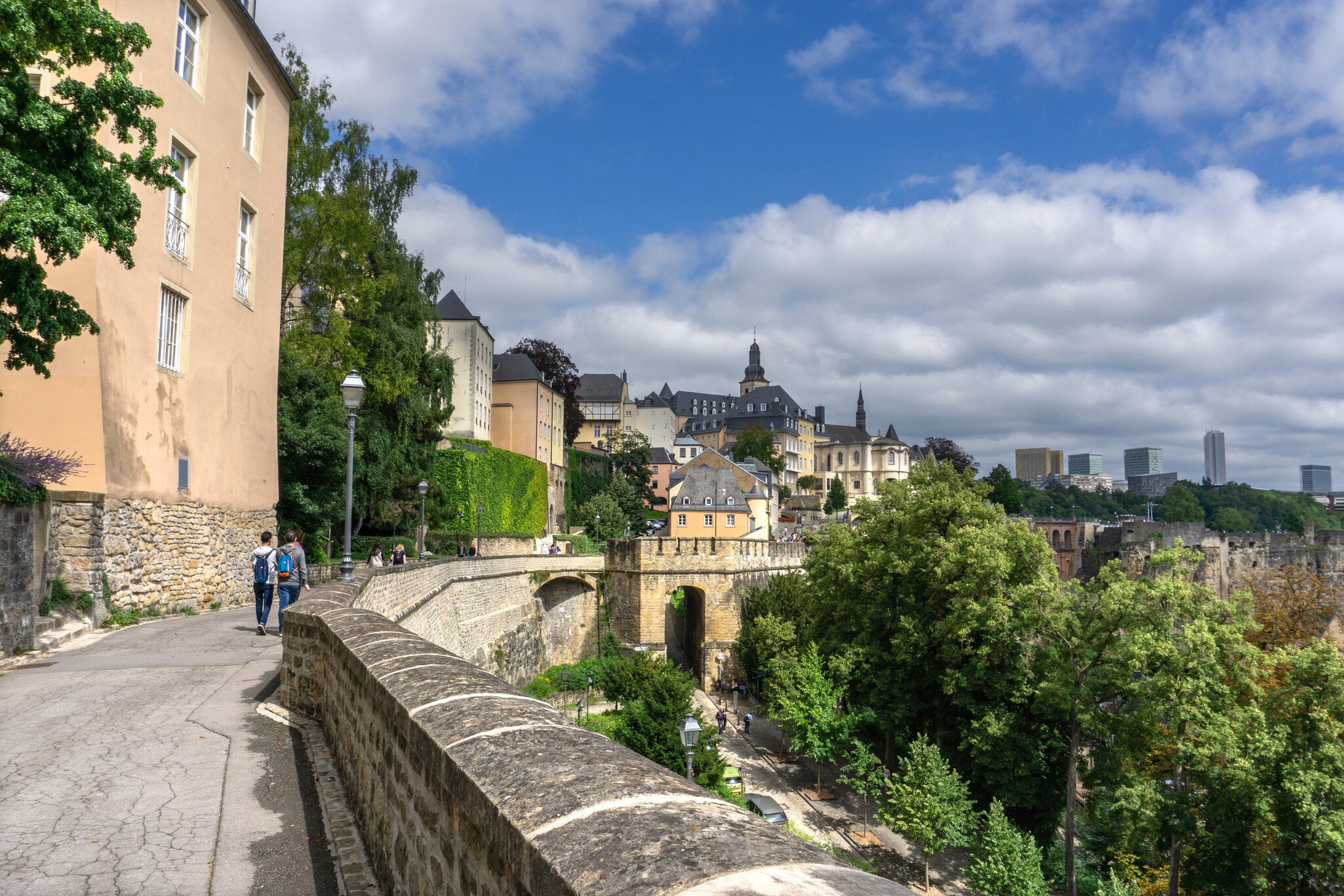 People walk along a pedestrian passageway consisting of the ramparts of a medieval city