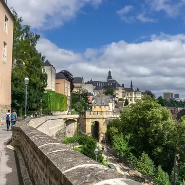 People walk along a pedestrian passageway consisting of the ramparts of a medieval city