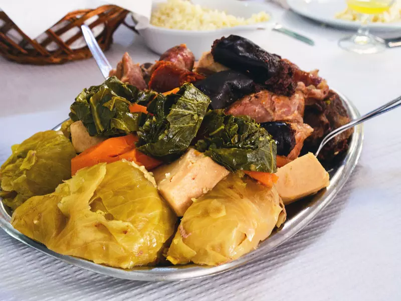 A plate of stew with meat, cabbage, carrots and other ingredients sits on a table.