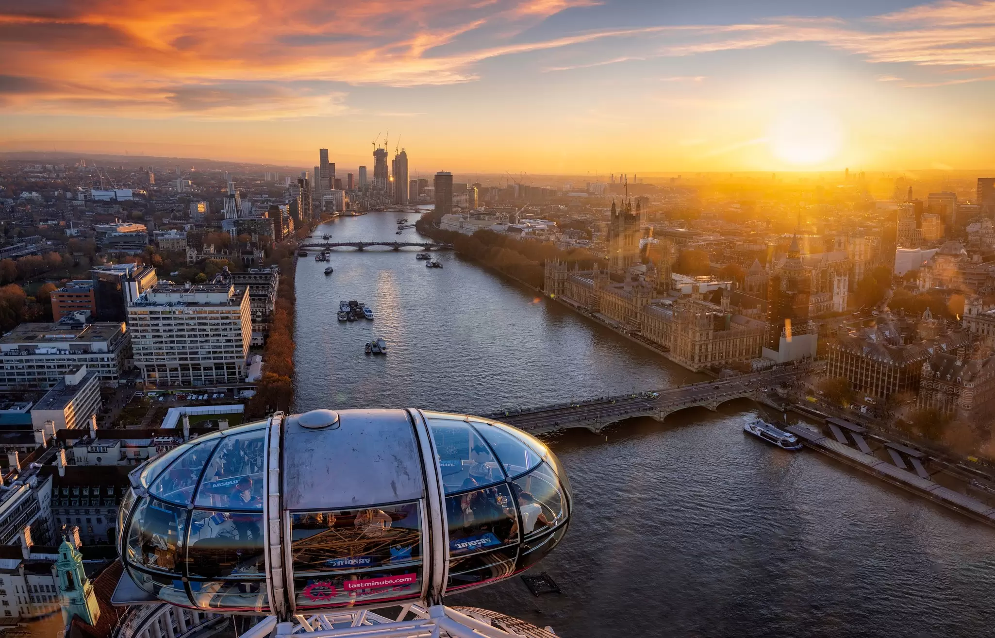 A giant Ferris wheel beside a river with views across London at sunset.